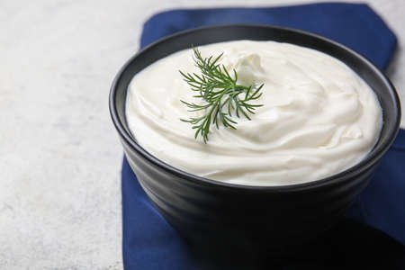 Bowl of tasty sour cream on light tableの写真素材