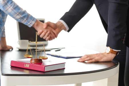 Woman and lawyer shaking hands in officeの写真素材