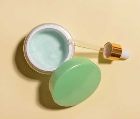 Jar of cream and dropper on color backgroundの写真素材