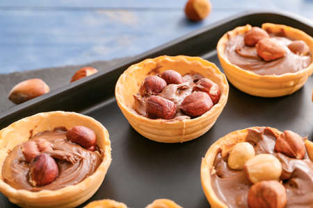 Tartlets with tasty chocolate paste and hazelnuts on tray, closeupの写真素材