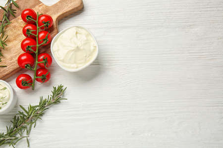 Tasty sour cream and tomatoes on white wooden tableの写真素材