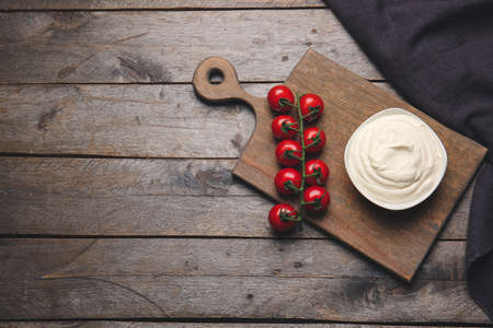 Bowl of tasty sour cream and tomatoes on wooden tableの写真素材