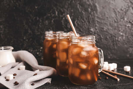 Mason jars of tasty iced coffee on dark backgroundの写真素材