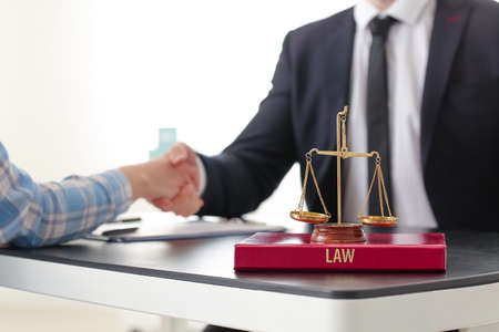 Woman and lawyer shaking hands in officeの写真素材