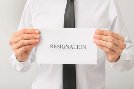 Man holding paper with text RESIGNATION on light backgroundの写真素材