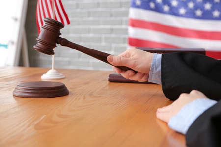 Female judge with gavel at table in courtroom, closeupの写真素材