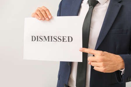 Man holding paper with text DISMISSED on light backgroundの写真素材