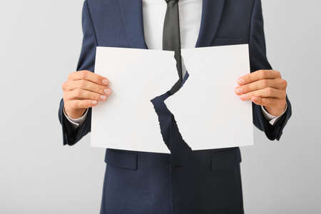 Man with torn paper on light background. Concept of dismissalの写真素材