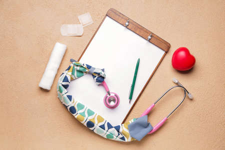 Stethoscope with cover, heart, clipboard and supplies on color backgroundの写真素材