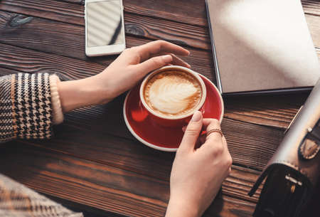 Woman drinking tasty cappuccino at wooden tableの写真素材