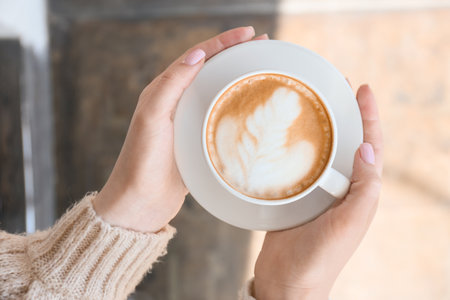 Woman with cup of tasty cappuccino outdoors, closeupの写真素材