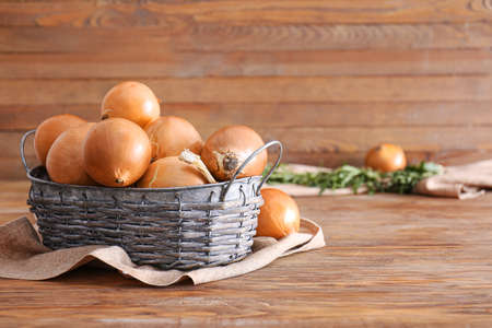 Basket with fresh raw onion on wooden tableの写真素材