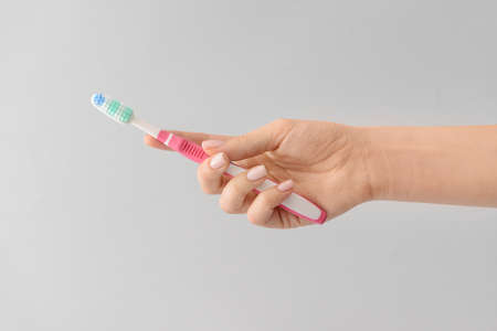 Female hand with tooth brush on light backgroundの写真素材