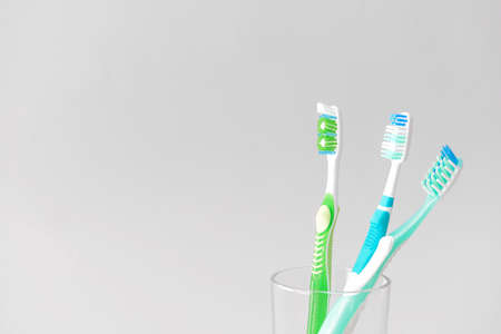 Tooth brushes in glass on light backgroundの写真素材