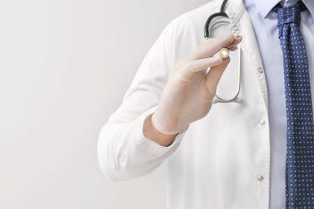 Male doctor with flashlight on gray background, closeupの写真素材