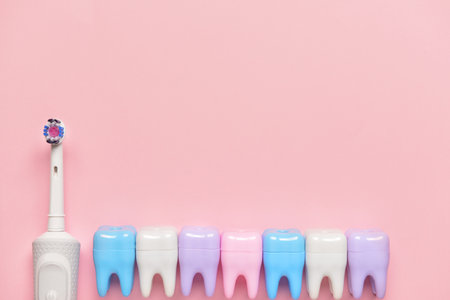 Electric tooth brush and plastic teeth on color backgroundの写真素材