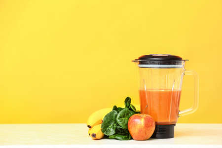 Blender with healthy smoothie and ingredients on color backgroundの写真素材