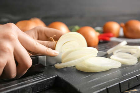 Woman cutting fresh raw onion on table, closeupの写真素材
