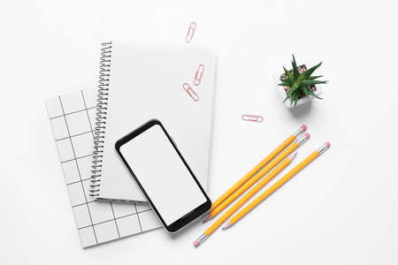 Mobile phone and stationery on white backgroundの写真素材