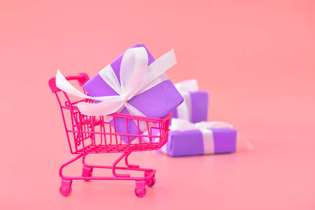 Birthday gift with shopping cart on color backgroundの写真素材