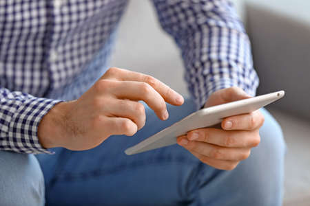 Young man with tablet computer at home, closeupの写真素材