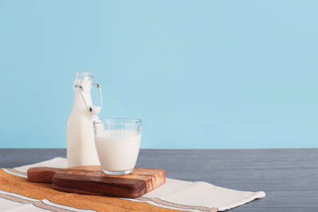 Glassware with fresh milk on table against color backgroundの写真素材