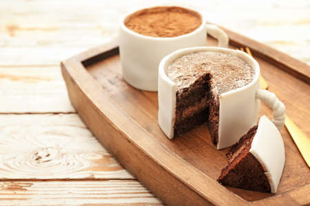 Chocolate cakes in shape of coffee cups on white wooden backgroundの写真素材