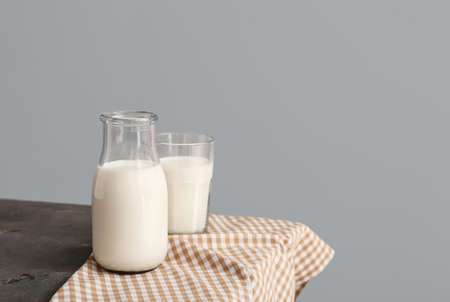 Glassware with fresh milk on table against gray backgroundの写真素材