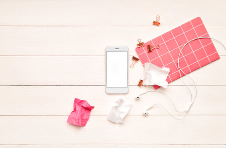 Mobile phone, earphones and stationery on wooden backgroundの写真素材