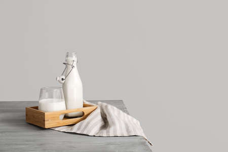 Glassware with fresh milk on table against gray backgroundの写真素材