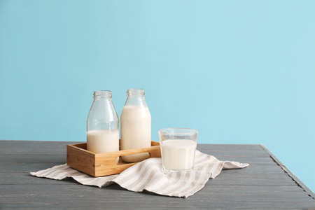 Glassware with fresh milk on table against color backgroundの写真素材