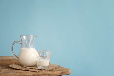 Glassware with fresh milk on table against color backgroundの写真素材