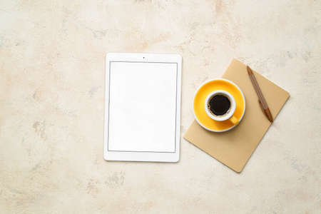 Tablet computer, cup of coffee and stationery on gray backgroundの写真素材