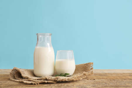 Glassware with fresh milk on table against color backgroundの写真素材