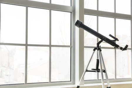 Modern telescope near window in roomの写真素材