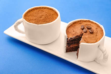 Plate with chocolate cakes in shape of coffee cups on color backgroundの写真素材