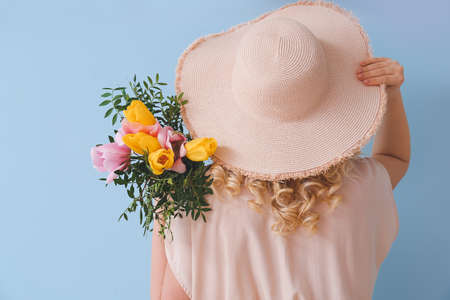 Beautiful young woman with bouquet of flowers on color backgroundの写真素材
