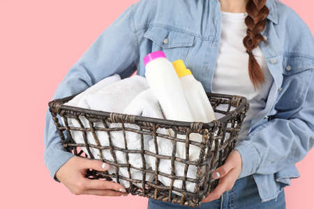 Beautiful young woman with laundry and detergents on color backgroundの写真素材