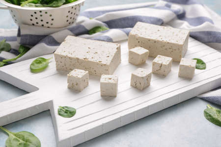 Board with tasty tofu cheese on tableの写真素材