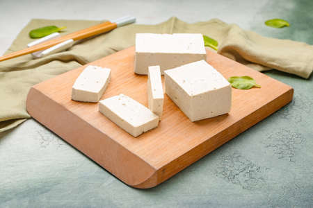 Board with tasty tofu cheese on color backgroundの写真素材