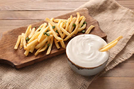 Bowl with tasty sour cream and french fries on tableの写真素材