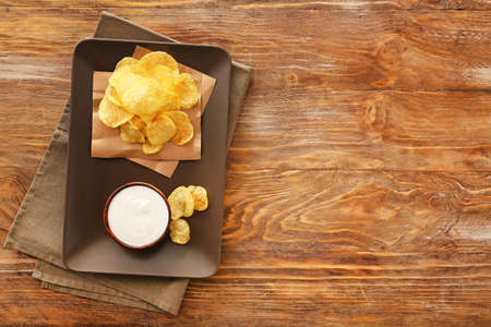 Plate with tasty sour cream and potato chips on tableの写真素材