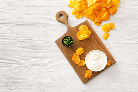 Tasty sour cream, green onion and potato chips on tableの写真素材