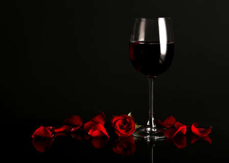 Glass of wine with rose flower on dark backgroundの写真素材