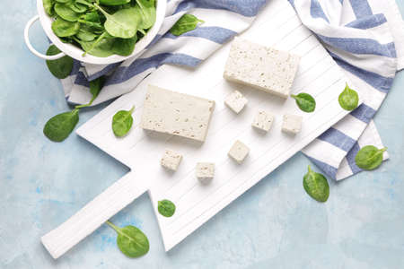 Board with tasty tofu cheese on color backgroundの写真素材
