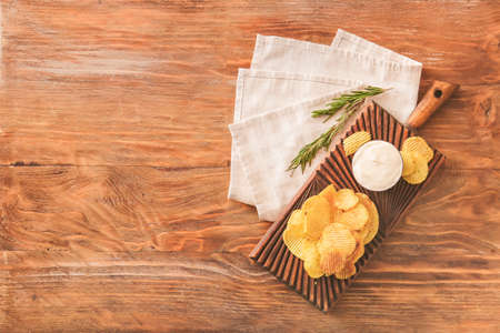 Board with tasty sour cream and potato chips on tableの写真素材