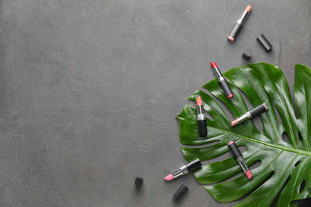 Different lipsticks and tropical leaf on gray backgroundの写真素材