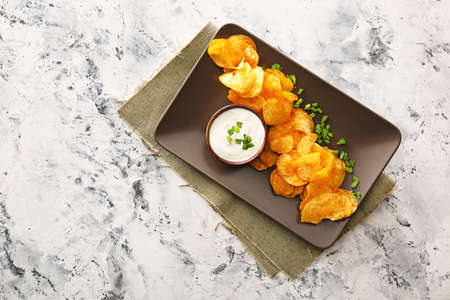 Tasty sour cream and potato chips on tableの写真素材