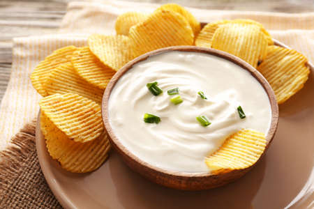 Tasty sour cream and potato chips on tableの写真素材