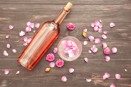 Bottle of wine, glass and rose petals on tableの写真素材